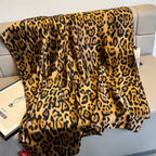 Leopard print blanket draped over a couch with a visible brand tag.