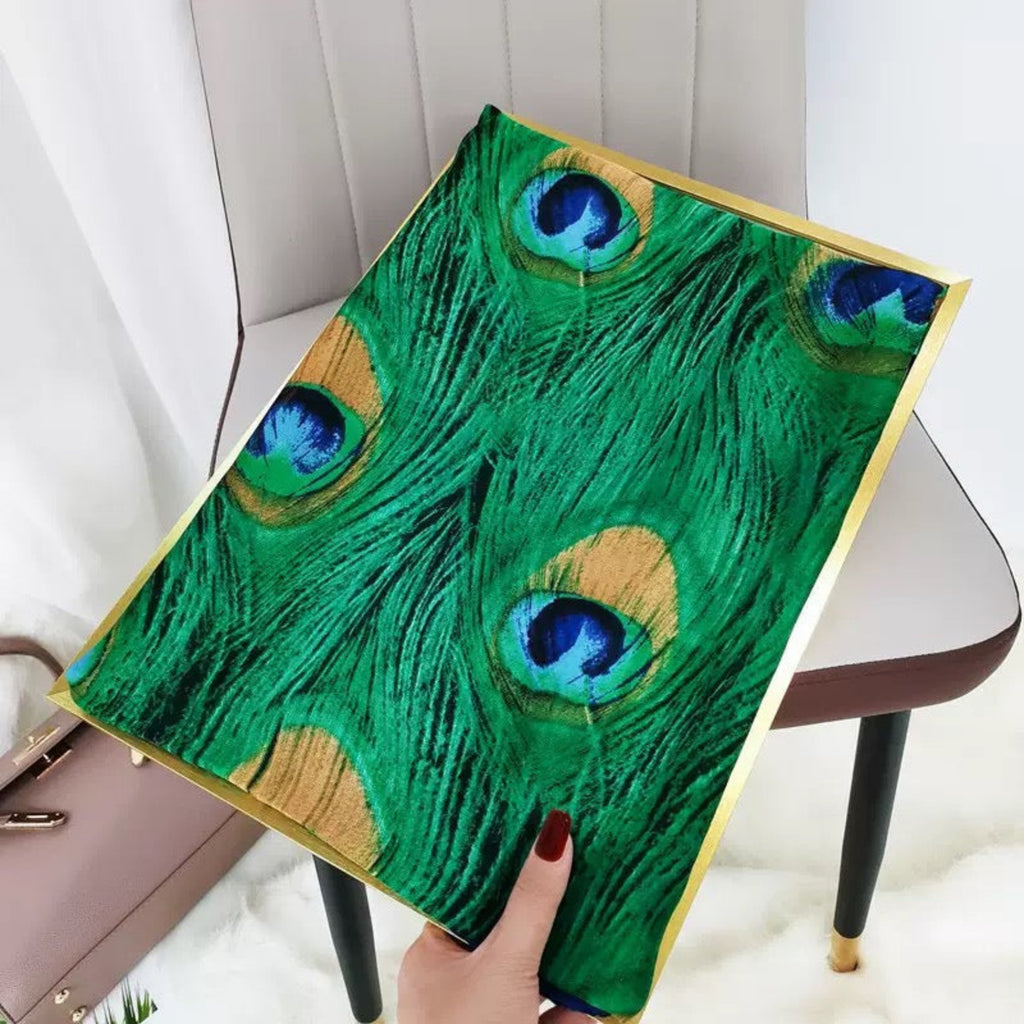 Hand holding a decorative item with peacock feather design on a chair.
