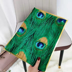 Hand holding a decorative item with peacock feather design on a chair.