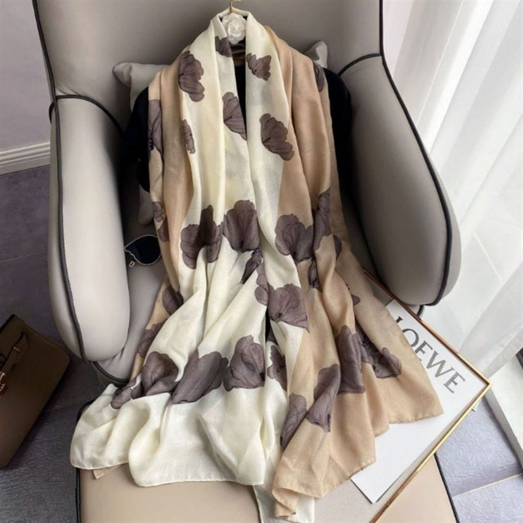 Beige scarf with brown butterfly patterns draped over a chair, with LOEWE branding visible.