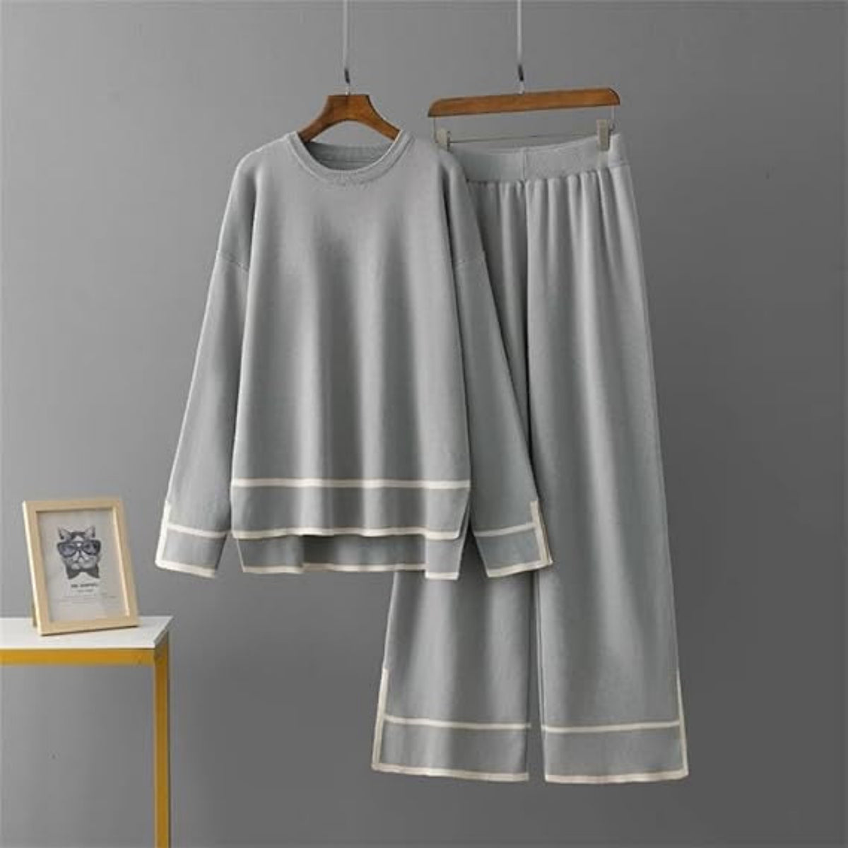 Gray pajama set with white trim on hangers against a gray background