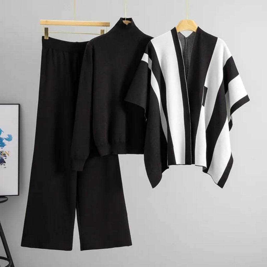 Black and white outfit with a poncho on a hanger against a gray background