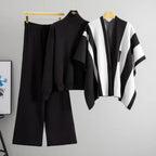 Black and white outfit with a poncho on a hanger against a gray background