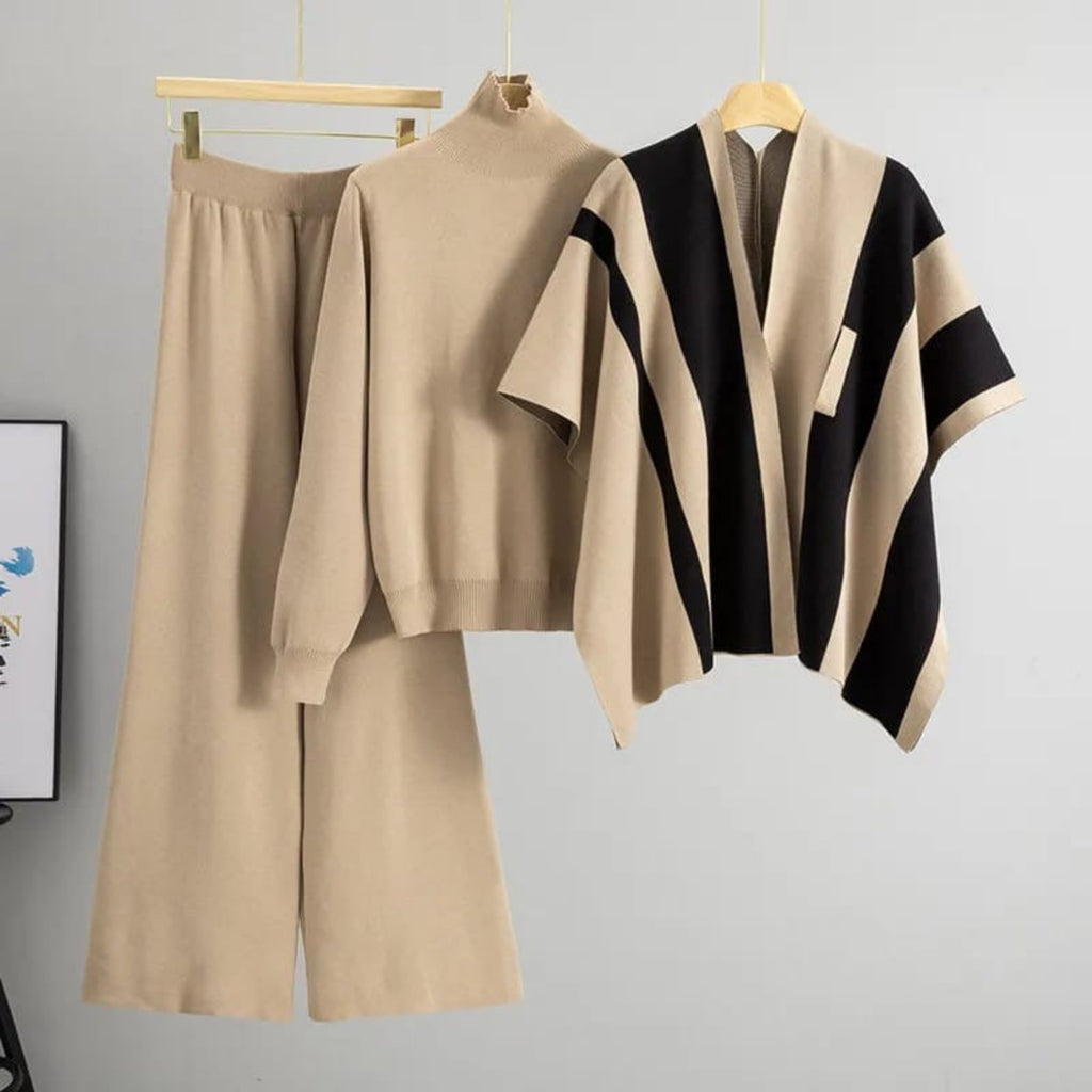 Beige outfit with a black and beige striped poncho on hangers against a gray background