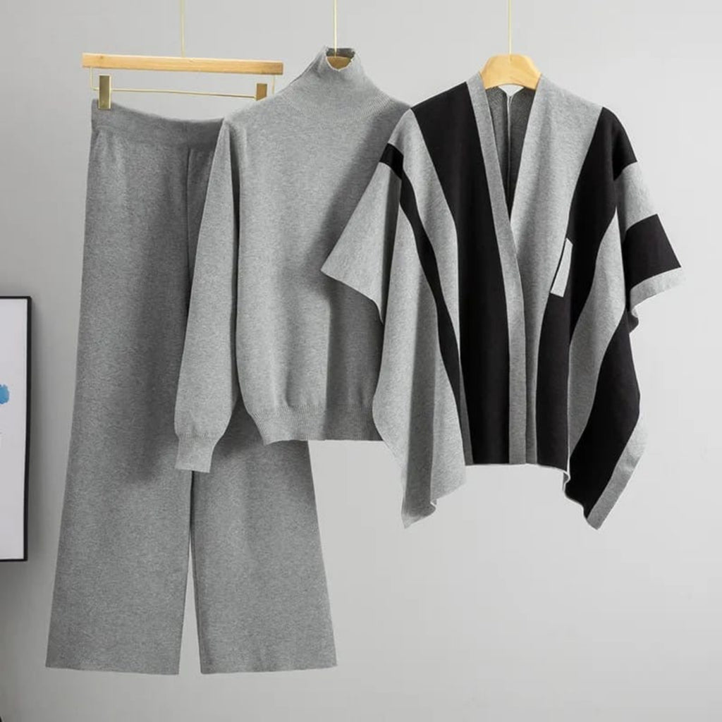 Gray sweater and pants set with a black and gray patterned shawl on hangers against a neutral background.