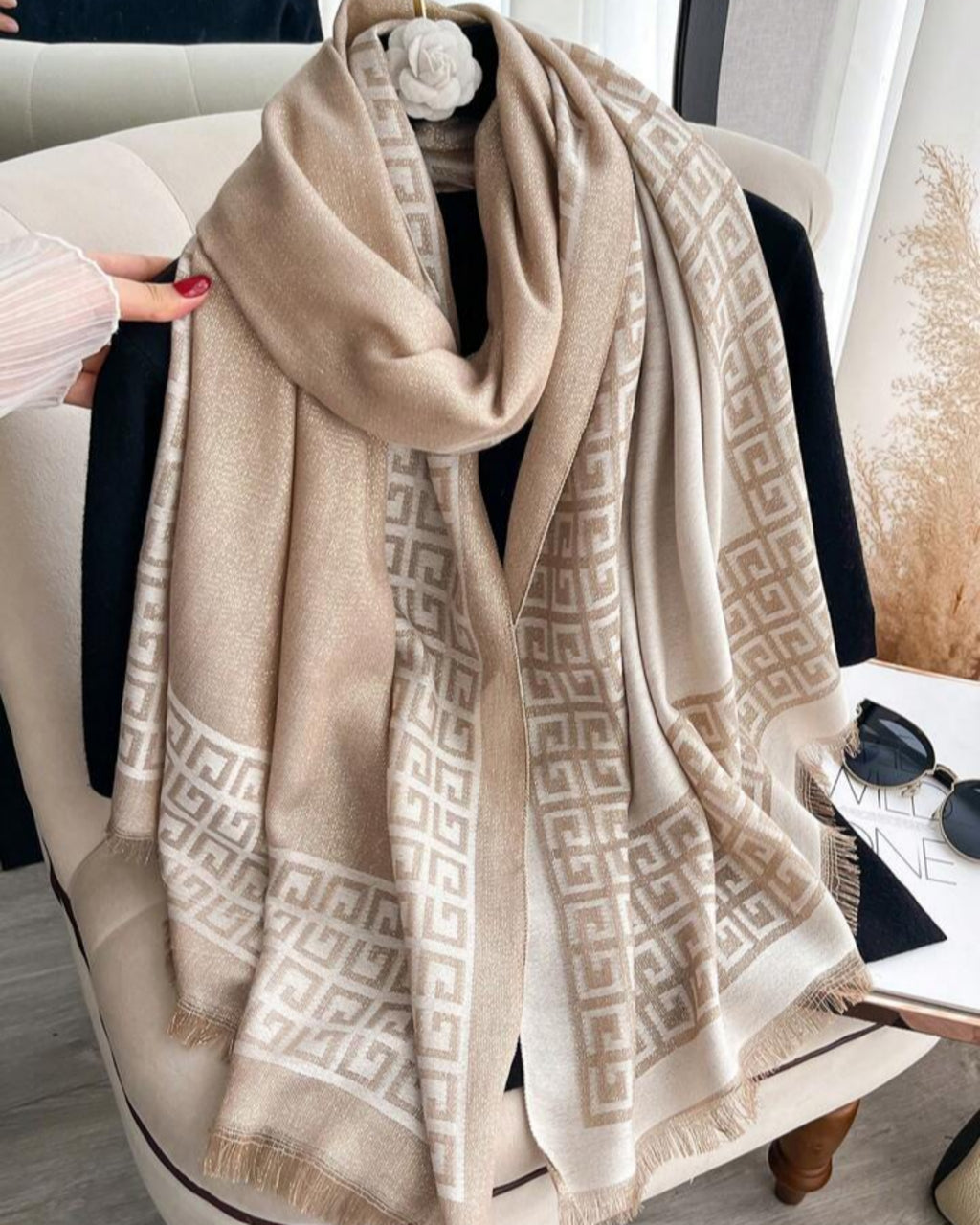 Beige patterned scarf draped over a chair with a neutral background