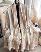 Beige patterned scarf draped over a chair with a neutral background