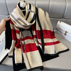 Striped scarf with red, beige, and black pattern on a gray surface