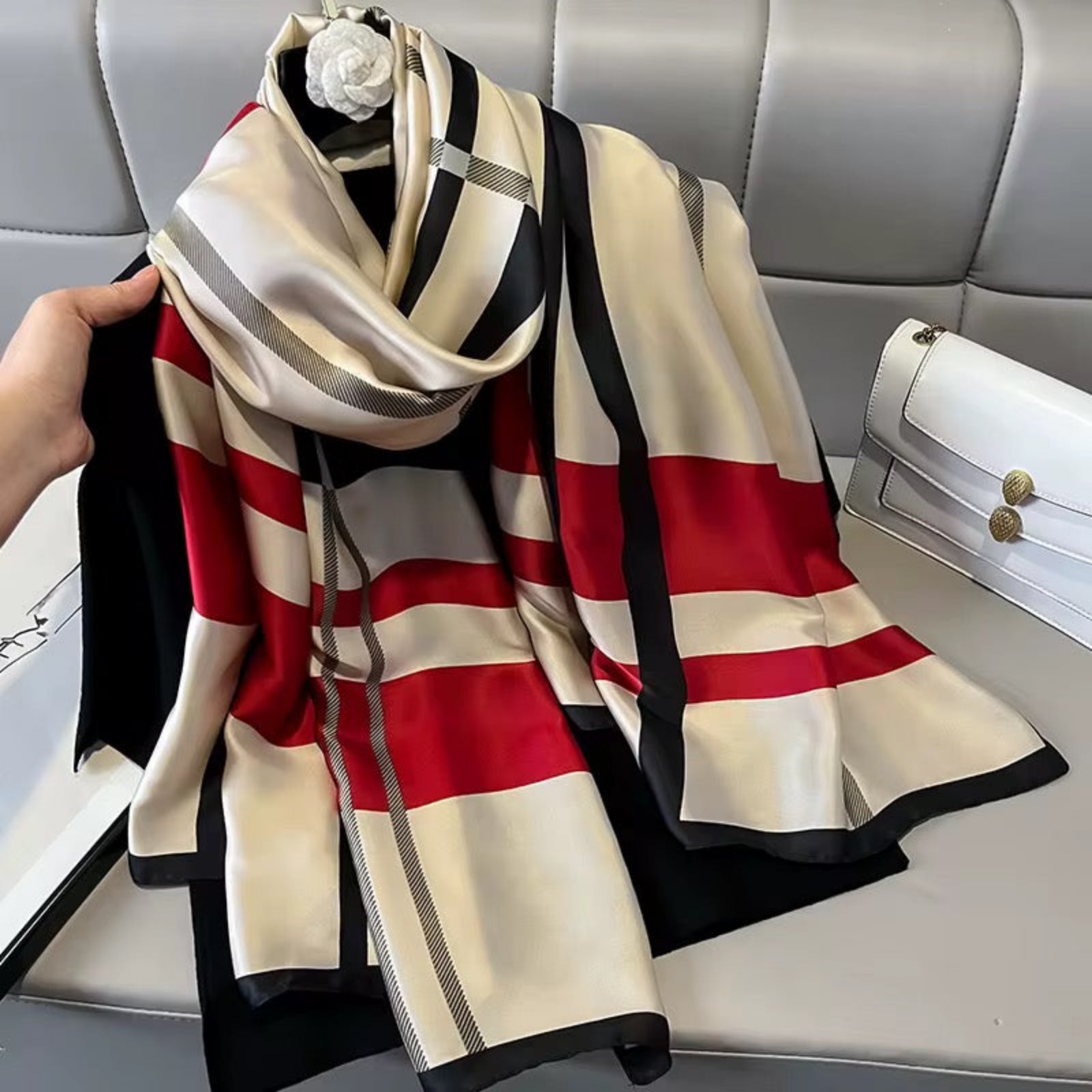 Striped scarf with red, beige, and black pattern on a gray surface