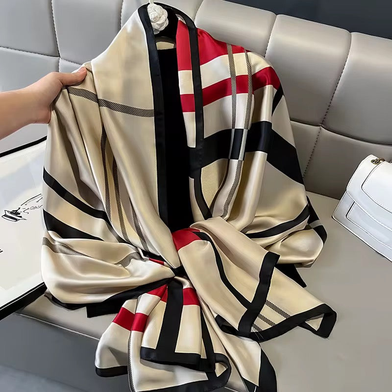 Checkered scarf with red, black, and beige stripes on a gray surface