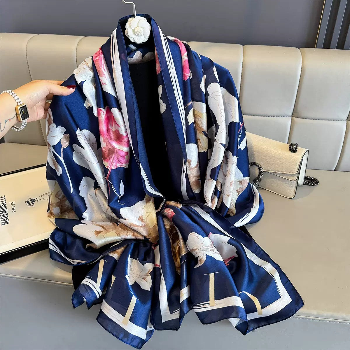 Navy blue scarf with floral and animal prints draped over a sofa.
