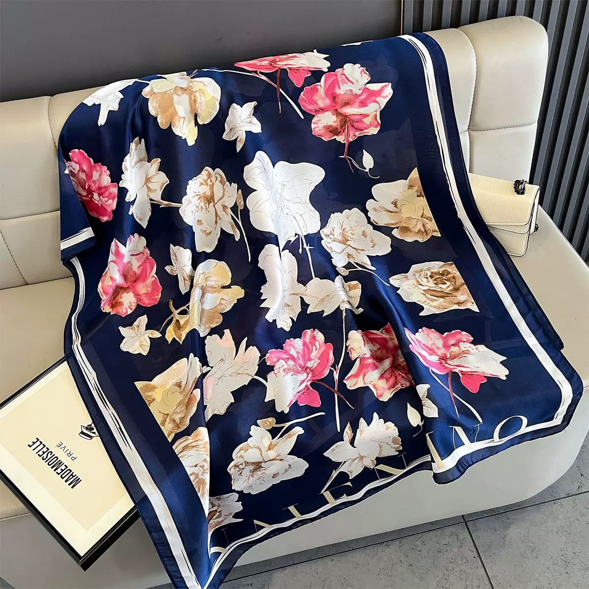 Floral-patterned blanket on a white couch with a visible brand name.