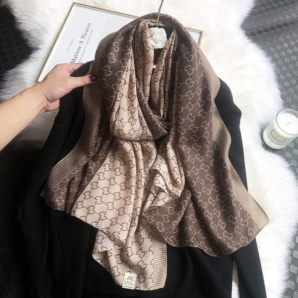 Brown patterned scarf draped over a black garment on a white surface.