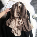 Brown patterned scarf draped over a black garment on a white surface.