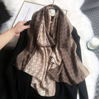 Brown patterned scarf draped over a black garment on a white surface.