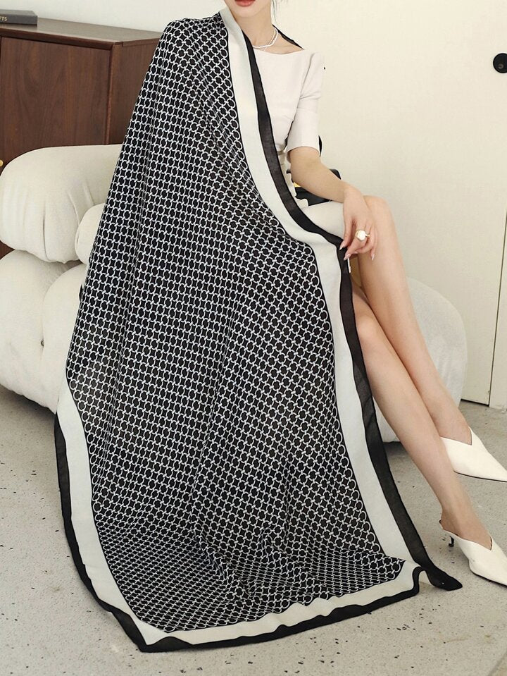 Person sitting on a couch with a black and white patterned blanket draped over them