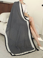 Person sitting on a couch with a black and white patterned blanket draped over them