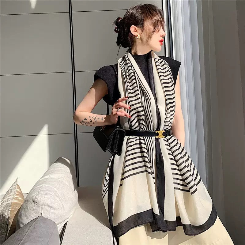 Woman wearing a black and white striped scarf in an indoor setting