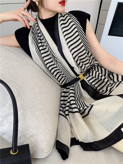 Woman wearing a black and white striped scarf sitting on a couch.