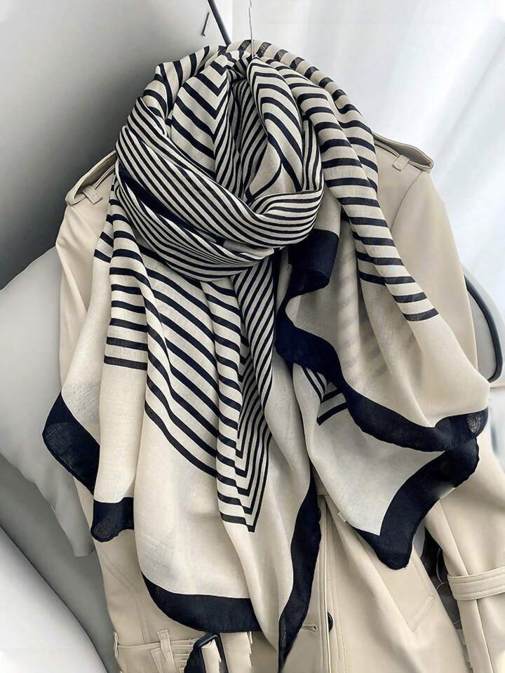 A striped Niket Opulent scarf in black and white, draped over a coat, with a focus on the intricate pattern.