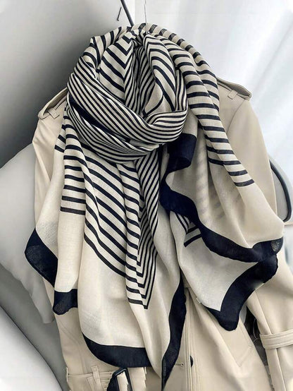 A striped Niket Opulent scarf in black and white, draped over a coat, with a focus on the intricate pattern.