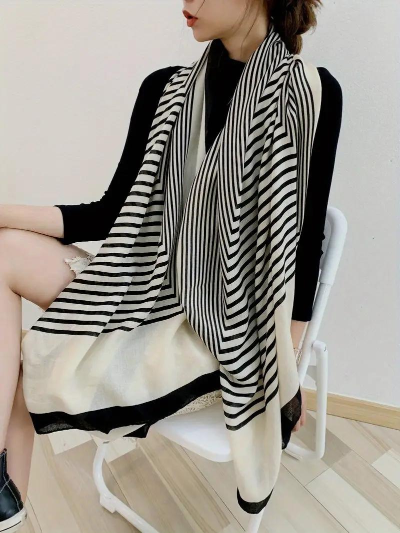 Person wearing a black and white striped scarf sitting on a chair.