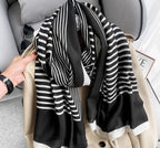 A striped Niket Opulent scarf in black and white, draped over a coat, with a focus on the intricate pattern.