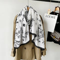 Beige trench coat with a white scarf featuring black floral patterns, hanging on a rack with a Loewe tag.