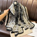 Person holding a floral patterned scarf with black and gold details on a brown leather chair.