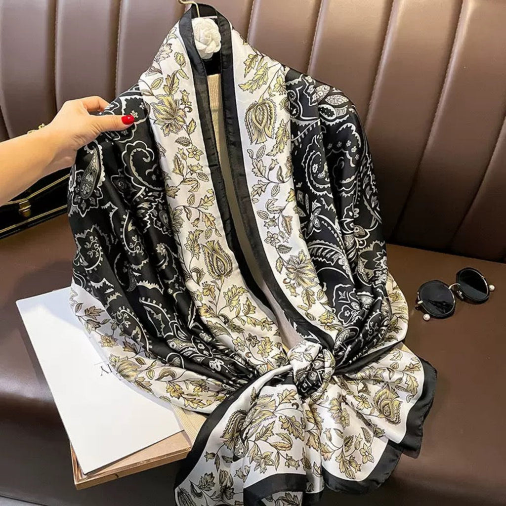 Black and white patterned scarf on a brown surface with a hand holding it.