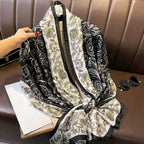 Black and white patterned scarf on a brown surface with a hand holding it.