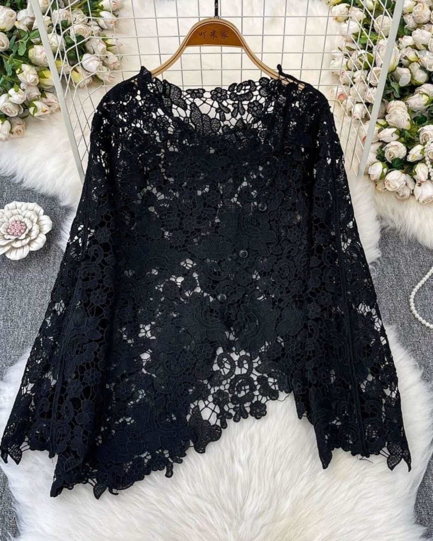 Black scalloped floral lace top on hanger flat lay