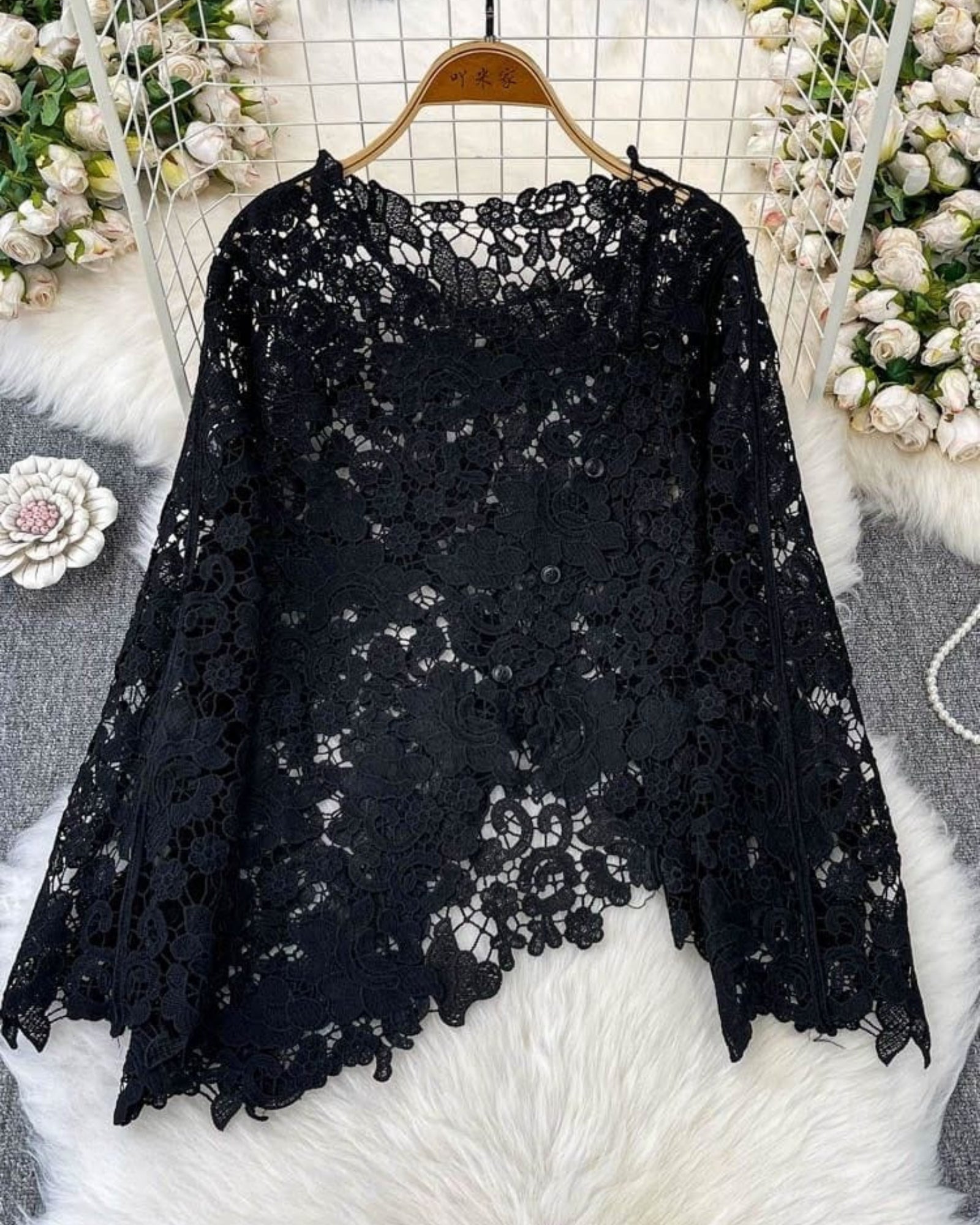 Black scalloped floral lace top on hanger flat lay