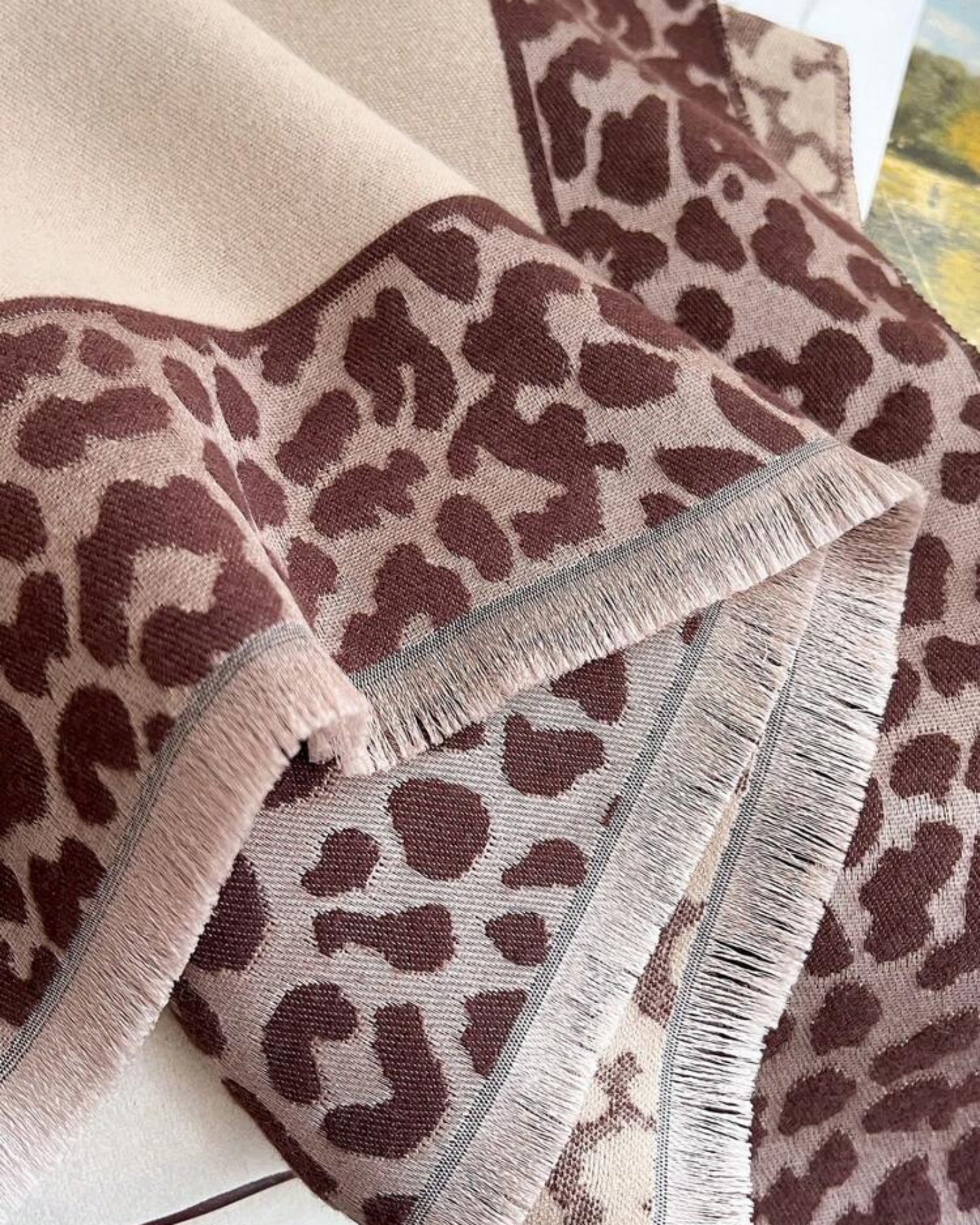 Leopard print blanket with fringes on a neutral background