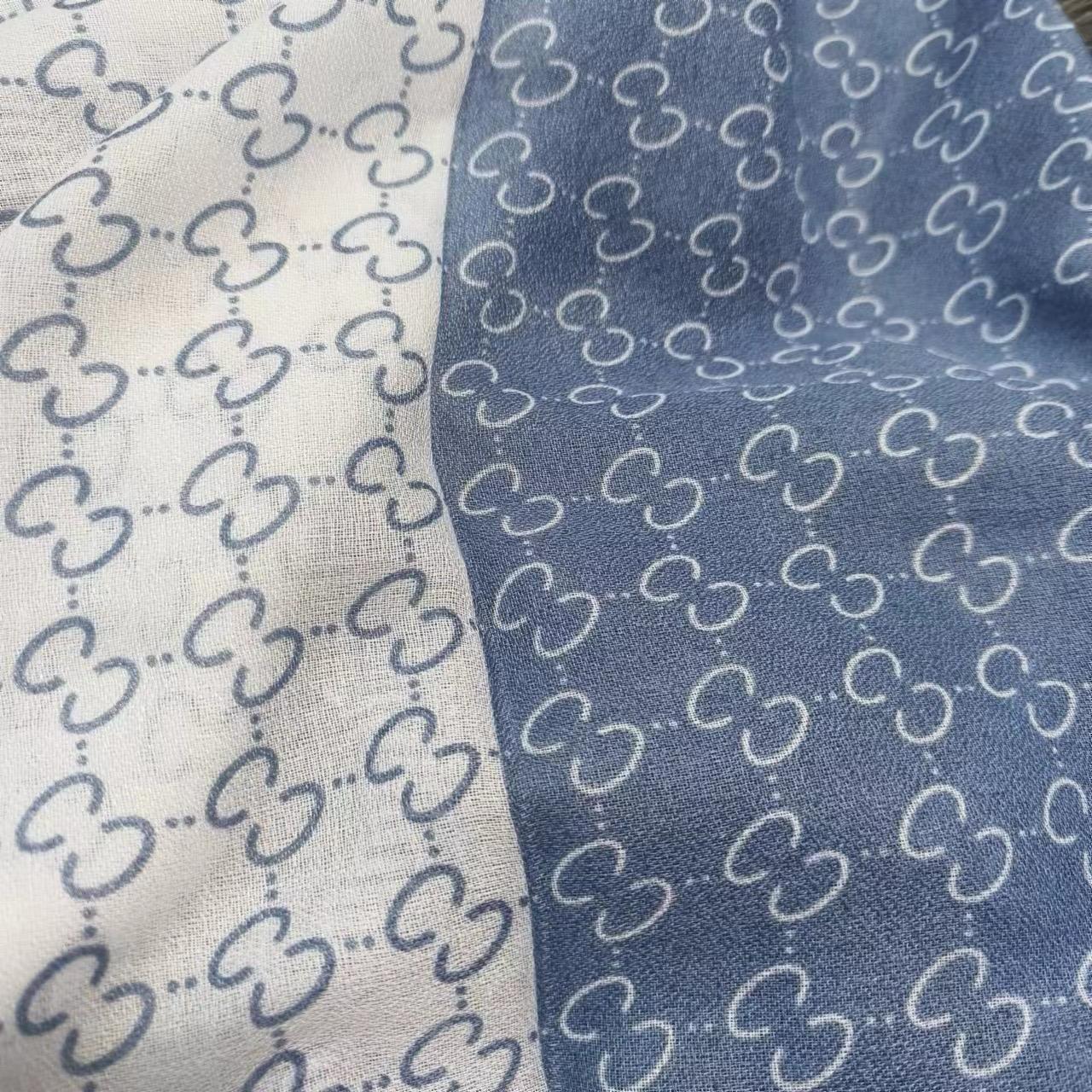 Close-up of fabric with a pattern of interlocking shapes on a white and blue background