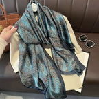 Blue patterned scarf being held over a white garment on a brown surface.