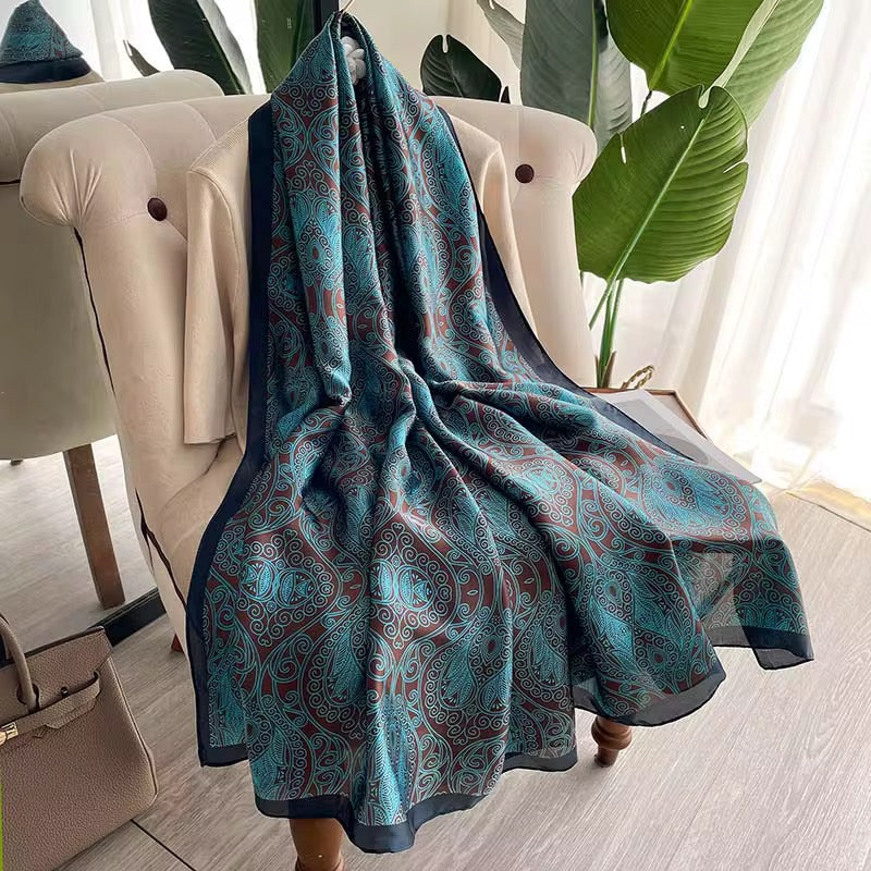 Blue patterned throw blanket draped over a chair in a room with plants and furniture.