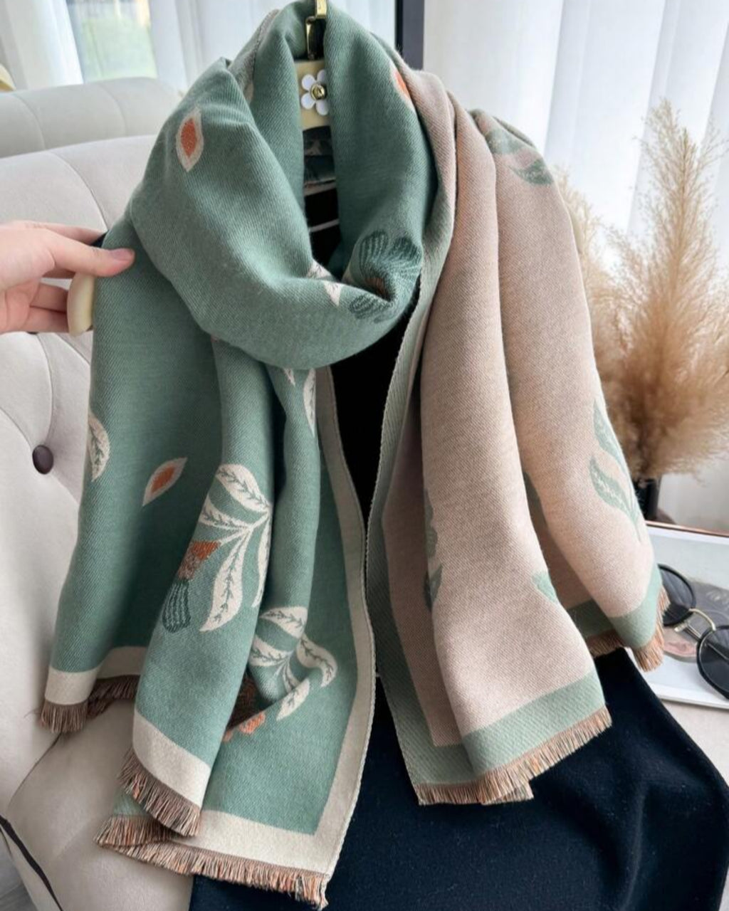 Two scarves, one green and one beige with floral patterns, draped over a chair.