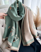 Two scarves, one green and one beige with floral patterns, draped over a chair.