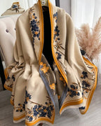 Beige blanket with floral patterns draped over a chair in a room.