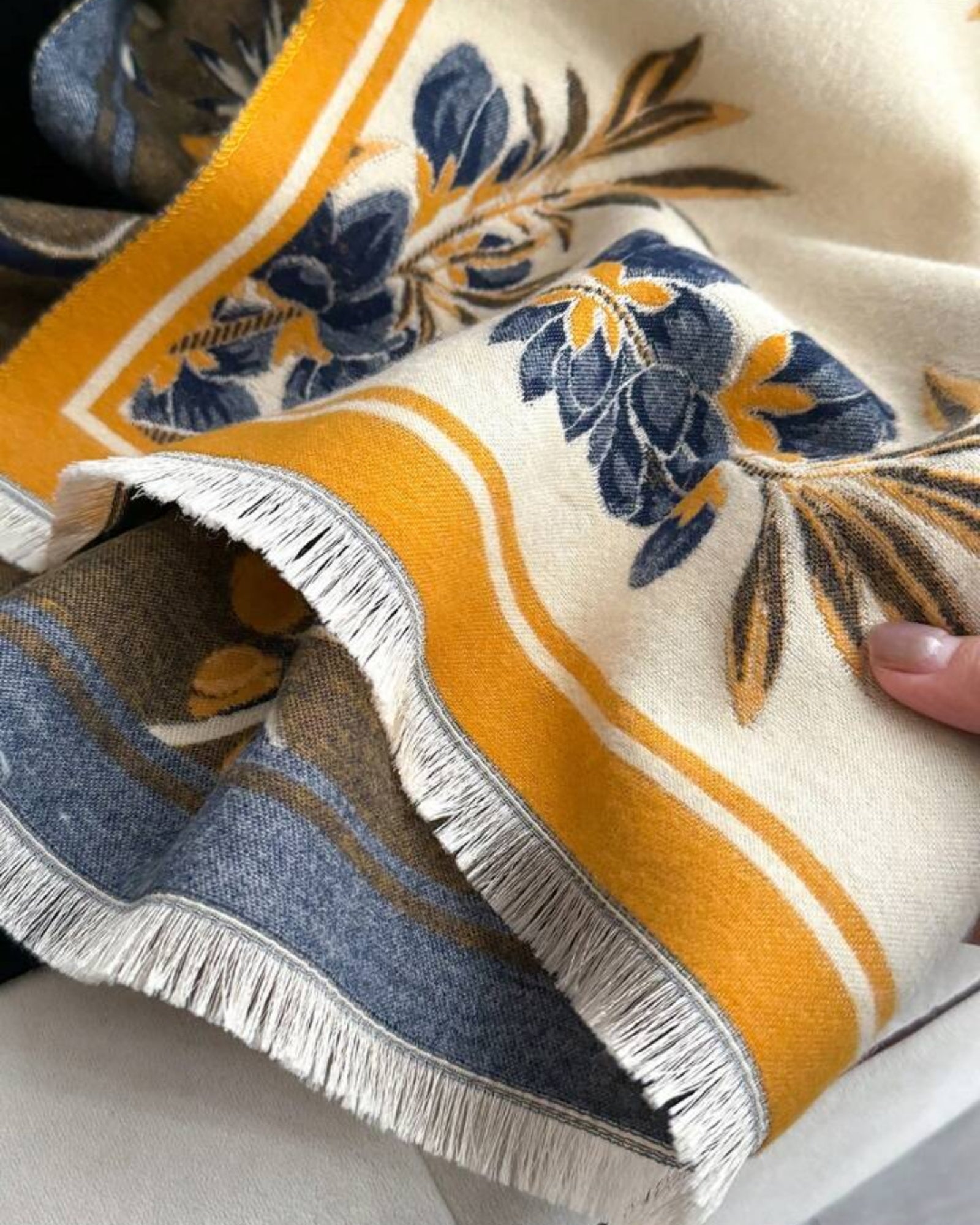 Close-up of a decorative fabric with floral patterns and fringes.