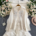 White lace blouse with floral embroidery on a hanger against a floral and textured background