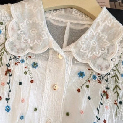 White lace blouse with floral embroidery on a hanger