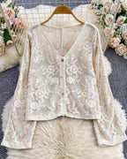 White lace cardigan on a hanger with floral decorations in the background