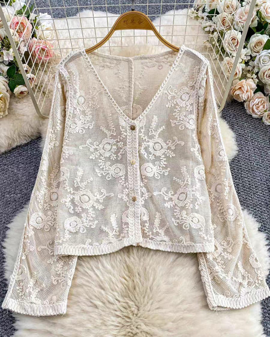 White lace cardigan on a hanger with floral decorations in the background