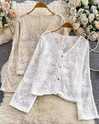 Two lace blouses on hangers with floral decorations in the background