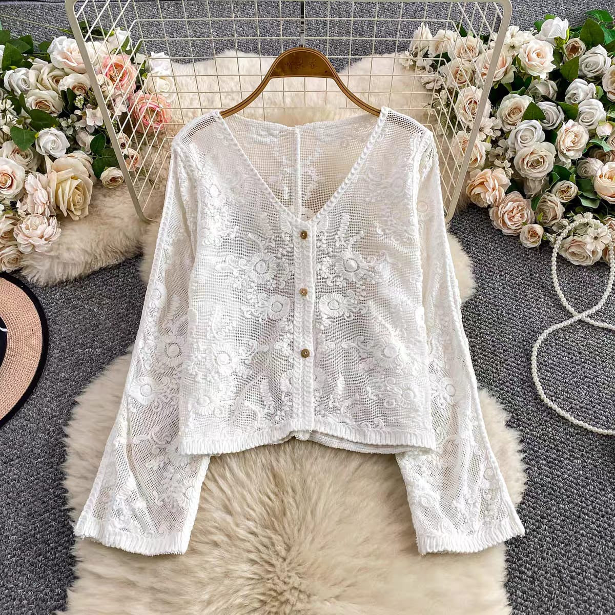 White lace top on a hanger with floral decorations in the background