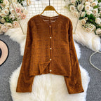 Brown knitted cardigan on a hanger with floral decorations in the background