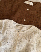 Two knitted cardigans, one brown and one beige, with 'lastlove' labels on a textured surface.