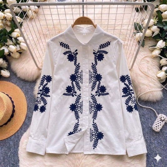 White shirt with blue floral embroidery on a hanger with decorative background